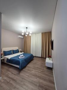 a bedroom with a blue bed and wooden floors at Love Nest in Almaty