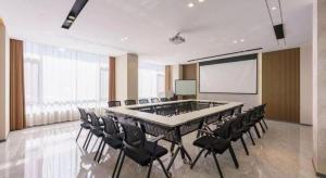 a conference room with a table and chairs and a screen at Jinjiang Inn - Xishan Road in Dalian