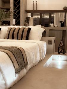 une chambre avec un lit avec des draps blancs et des oreillers dans l'établissement Runik Beach Club & Resort - Adults Only, à Siquijor