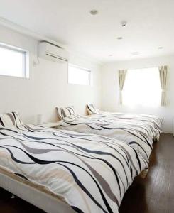 Cette chambre blanche dispose de 2 lits et de 2 fenêtres. dans l'établissement Shima Stay holoholo, à Zamami