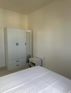 a white bedroom with a bed and a cabinet at STO Tower A Hulhumale Phase 2 in Hulhumale