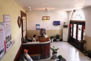 a woman sitting at a counter in a restaurant at Shell Zaozhuang Taierzhuang Ancient City East Gate Hotel in Yanzibu