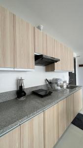 Una cocina con gabinetes de madera y encimera. en Romantic 2BR Haven with Gentle Lighting, en Mandurriao