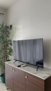 TV de pantalla plana en la parte superior de un armario de madera en Romantic 2BR Haven with Gentle Lighting, en Mandurriao