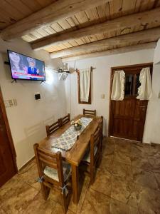 ein Holztisch und Stühle in einem Zimmer mit einem Fernseher in der Unterkunft Complejo San isidro in San Rafael