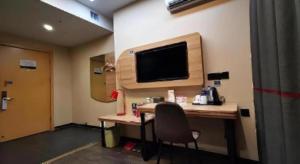 une pièce avec un bureau avec une télévision sur un mur dans l'établissement Thank Inn Hotel Anhui Fuyang Funan County Yunhe Dong Road, à Chengjiao