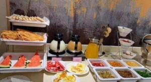a table topped with trays of different types of food at GreenTree Inn Nantong Haian Kaifa District Express Hotel in Maotangqiao