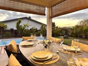 a table with plates and wine glasses on a patio at Villa Parenthèse - Piscine & Bungalow - 8 Pers in Trois Bassins +38 photos