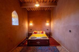 a bedroom with a bed in the corner of a room at Riad Imuhar Prestige - Mhamid Desert Retreat in Mhamid