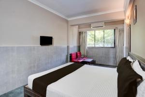 a hotel room with a bed and a tv at Hotel O Calangute-Baga Crossway Formerly Rustic Village in Calangute