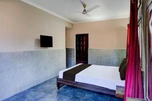 een slaapkamer met een bed en een tv aan de muur bij Hotel O Calangute-Baga Crossway Formerly Rustic Village in Calangute