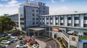a large building with cars parked in a parking lot at Jinjiang Metropolo Shanghai Minhang in Shanghai