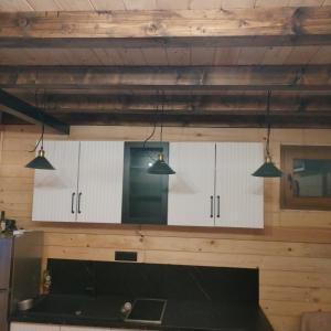 a kitchen with white cabinets and lights on the wall at Brvnara Iva in Kolašin