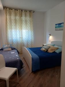a bedroom with two beds and a chair in it at Appartamento Chiara in Roseto degli Abruzzi