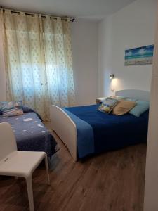 a bedroom with two beds and a chair in it at Appartamento Chiara in Roseto degli Abruzzi
