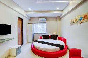 a bedroom with a bed and a red chair at Hotel O Elite Stay in Pune +22 photos