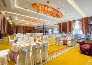 Zhangjiagang Jiangnan Garden Hotel في Xiwujieqiao: قاعة حفلات كبيرة مع طاولات وكراسي بيضاء