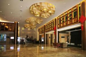 Zhangjiagang Jiangnan Garden Hotel في Xiwujieqiao: ردهة بها ثريات في مبنى به ردهة