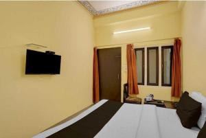 ジャイプールにあるHotel O Jagatpura Central Railway Station Jaipurのベッドと壁にテレビが掛かった寝室