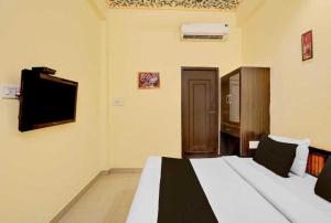 ジャイプールにあるHotel O Jagatpura Central Railway Station Jaipurのベッドと薄型テレビのある寝室