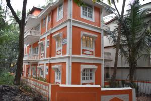 an orange and white building with trees in front of it at SkyView Villa in Candolim