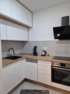 a kitchen with white cabinets and a sink at Hari Apartmani Oaza in Tuzla