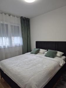 a bedroom with a large bed with two green pillows at Hari Apartmani Oaza in Tuzla