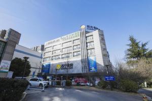 a building with a sign on the side of a street at Vatica HeFei Baishuiba BHG Hotel in Hefei