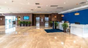 a large lobby with a blue wall and a lobby with plants at Holiday Inn Express Tianjin Dongli By IHG in Tianjin