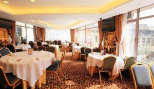 a restaurant with white tables and chairs and windows at Towns Well Motel in Macau