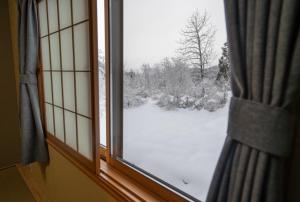 a window with a view of a snow covered yard at urara house guesthouse in Wada