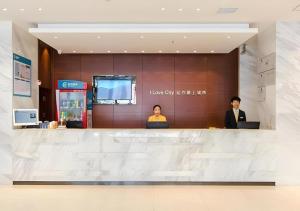 two people sitting at a counter in a lobby at City Comfort Inn Xiaogan Chengzhan Road in Xiaogan