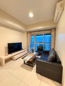 a living room with a black couch and a television at 2BR Sunset View Deluxe Suite in Manila