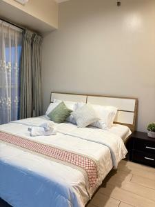 a bedroom with a bed with white sheets and a window at 2BR Sunset View Deluxe Suite in Manila
