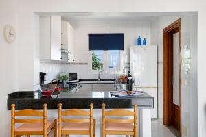 a kitchen with a counter with chairs and a refrigerator at Casa Cactus in Haría