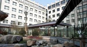 a large building with a building with a fountain in front of it at Hotel Ramada Plaza Hangzhou Xiaoshan in Chang-shen-tien