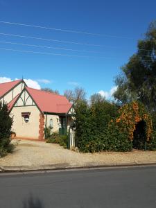 a house with a red roof and a bush with flowers at The Dove Cote in Tanunda