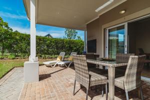 a patio with a table and chairs and a television at Manor One Kingswood Golf Estate in George