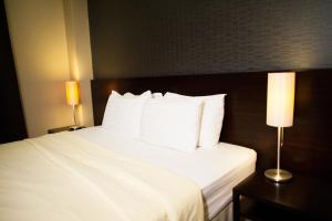 a hotel room with a bed with white sheets and pillows at Baansilom Soi 3 in Bangkok