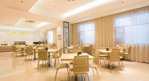 a restaurant with tables and chairs in a room at City Comfort Inn Xiangyang Railway Station in Xiangyang