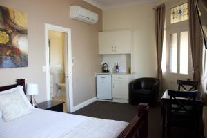 a bedroom with a bed and a chair and a kitchen at Balcony On Sixth Lodge in Murray Bridge