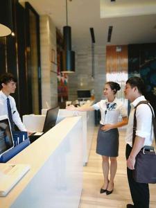two people standing at a counter in an office at Echarm Hotel Danzhou Xiari Plaza in Danzhou