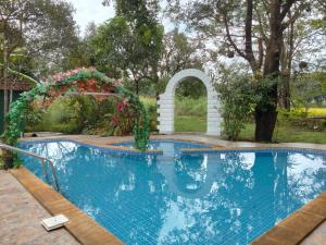 a swimming pool in a yard with an arch and flowers at Riyasatkar Heritage Resort in Khamshet