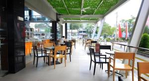 un restaurant avec des chaises et des tables et une personne en arrière-plan dans l'établissement G'Sign Hotel Banjarmasin, à Sungai Lutus