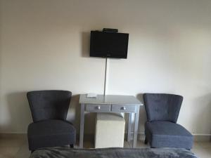 Duas cadeiras e uma mesa com uma televisão na parede em Larkspur Place em East London
