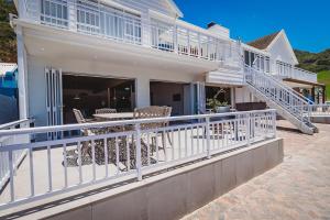 a white house with white railings and a patio at Beachfront property, Victoria Bay, Garden route in Victoria Bay