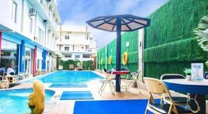 GeutieueにあるHotel Grand Permata Hatiのテーブルとパラソルのあるプール