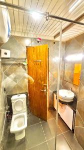 Un baño con inodoro y puerta de madera. en Rajmahal Inn Dalhousie, en Dalhousie