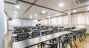 une salle de classe vide avec des tables, des chaises et un écran dans l'établissement Warmly Hotel Suzhou Jinji Lake Ligongdi Branch, à Suzhou