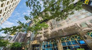 un grand bâtiment avec des arbres devant lui dans l'établissement Hotel Floce, à Pup'yŏng-dong